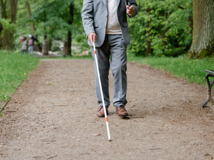 失明により白杖をつく男性