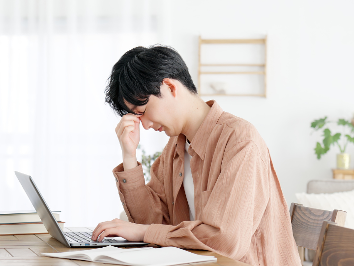 PCを見て目の疲れを感じる男性